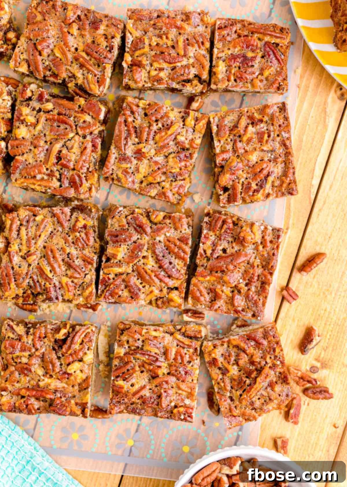 Overhead photo of pecan pie bars neatly sliced and arranged on a rustic wooden table.