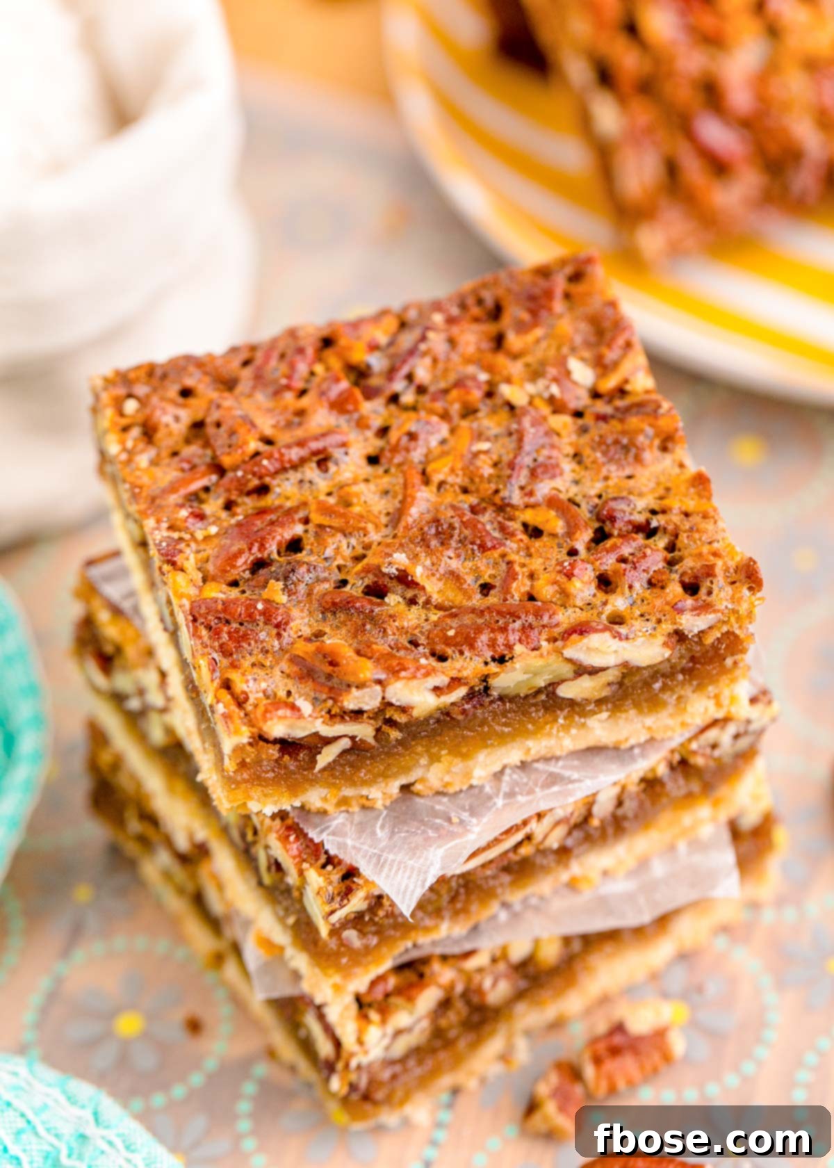 A stack of three pecan bars resting on parchment paper, ready to be served.