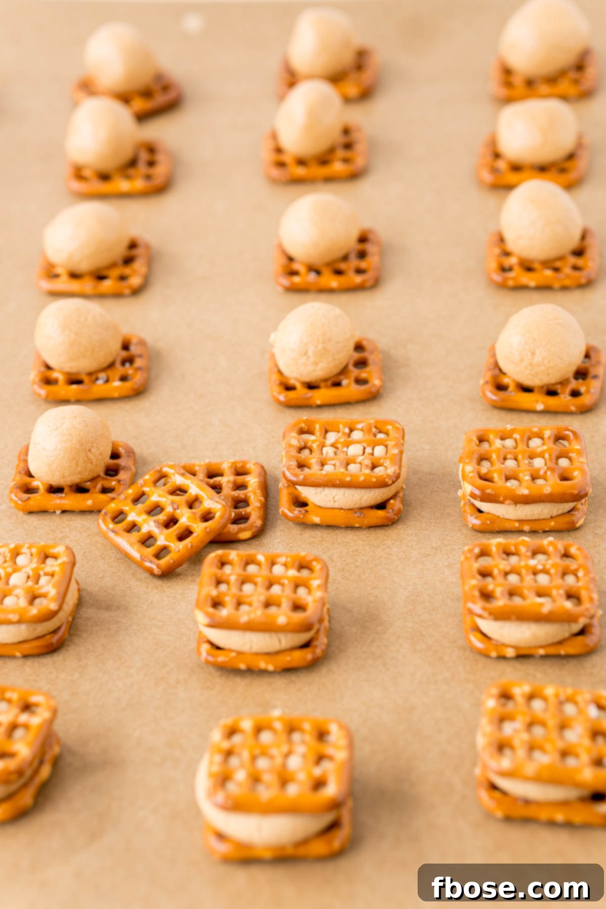 Peanut butter pretzel bites being made on a parchment lined baking sheet.
