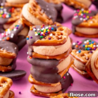 Three peanut butter pretzel bites stacked on a pink surface with more around it.