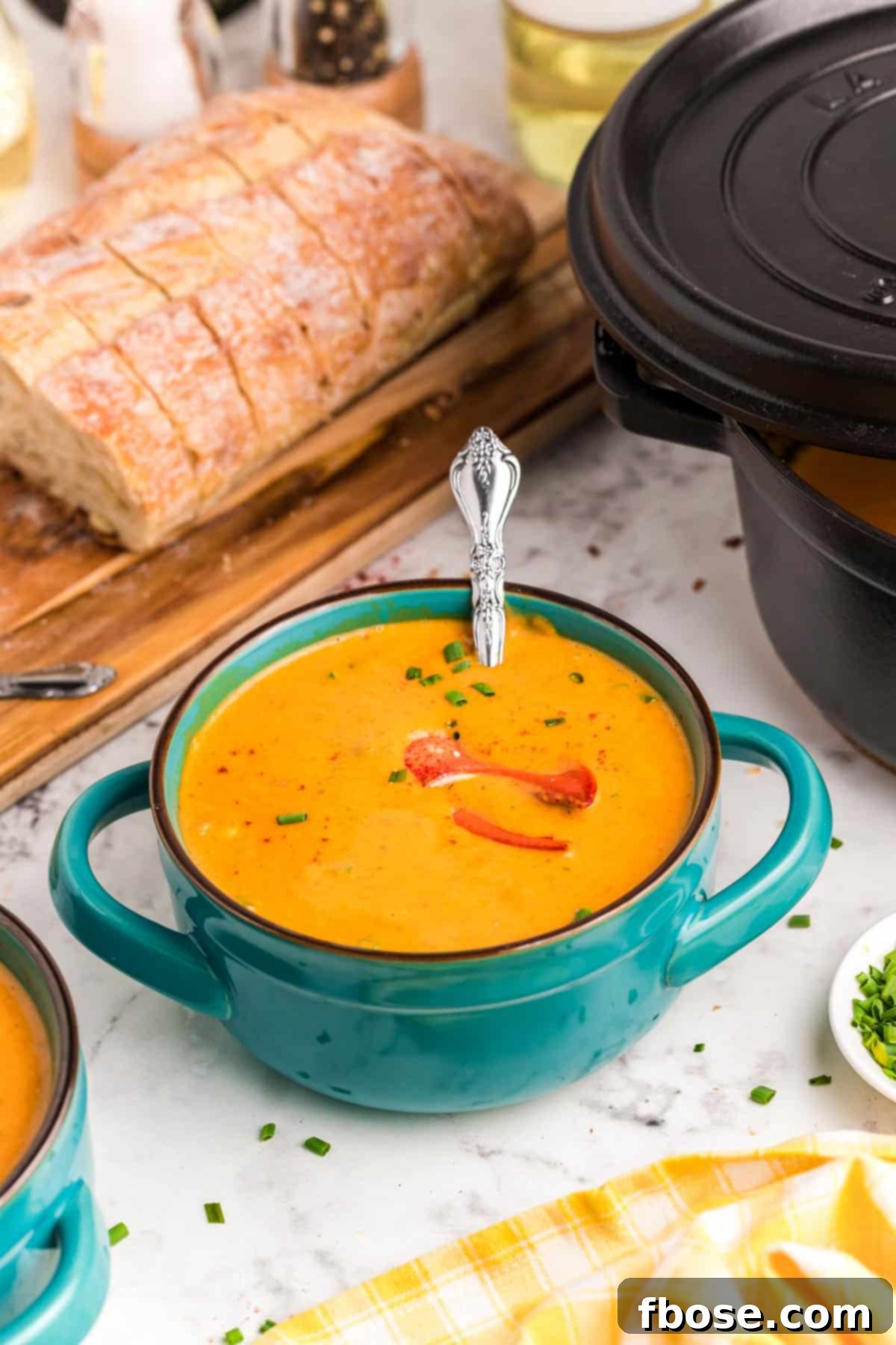 Ultimate Lobster Bisque From Scratch 6 Lobster bisque in a teal serving bowl with bread in the background.