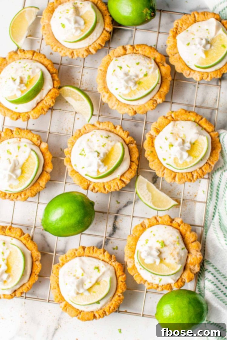 Overhead photo of freshly baked key lime pie cookies cooling on a wire rack, surrounded by fresh limes.