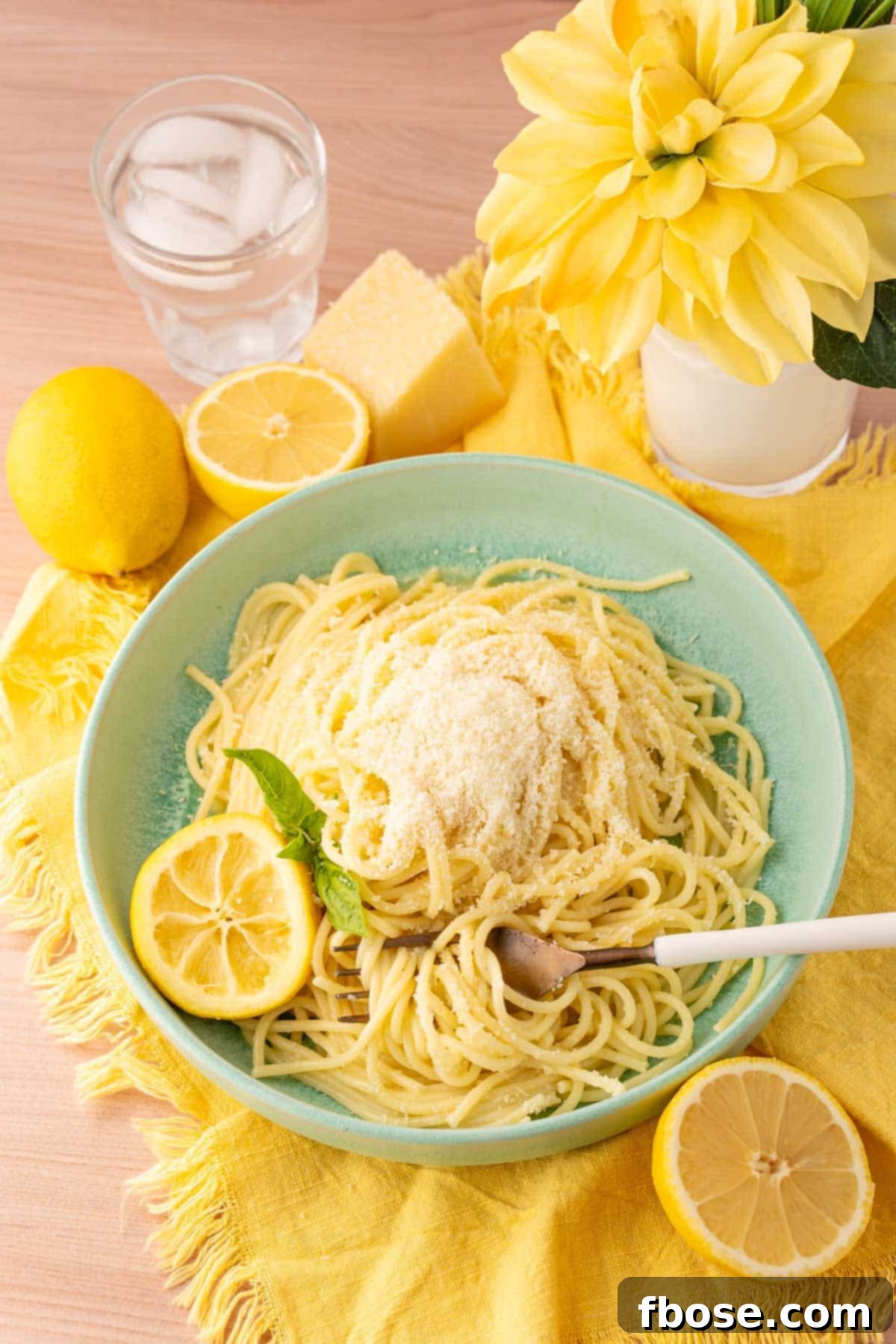 Lemon Butter Pasta (Spaghetti Limone) in a mint green bowl on a yellow cloth napkin, ready to be enjoyed.