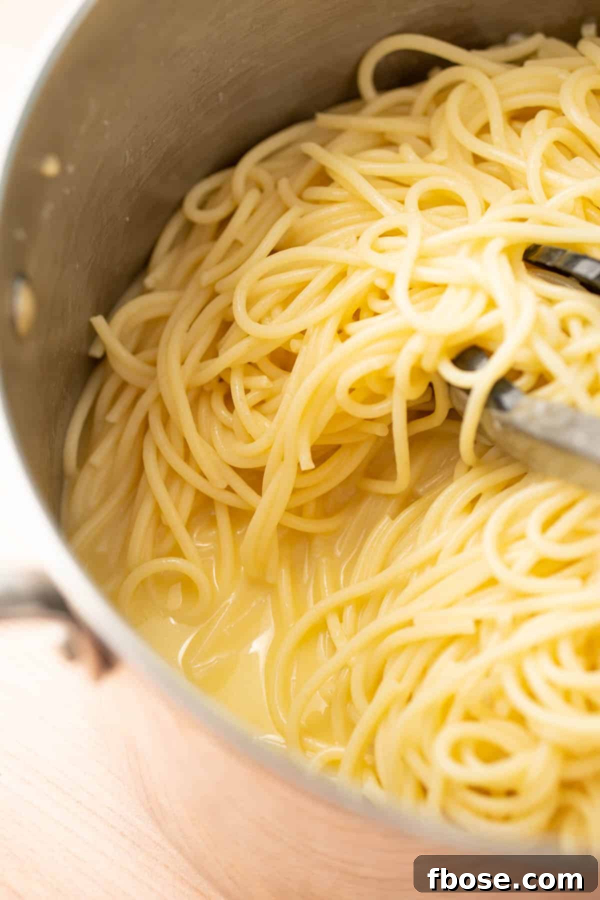 Spaghetti in a pot with perfectly emulsified lemon butter sauce, ready to be served.
