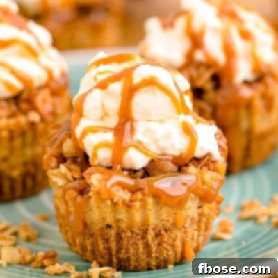 Mini caramel apple cheesecakes topped with whipped cream and caramel drizzle on a blue plate.