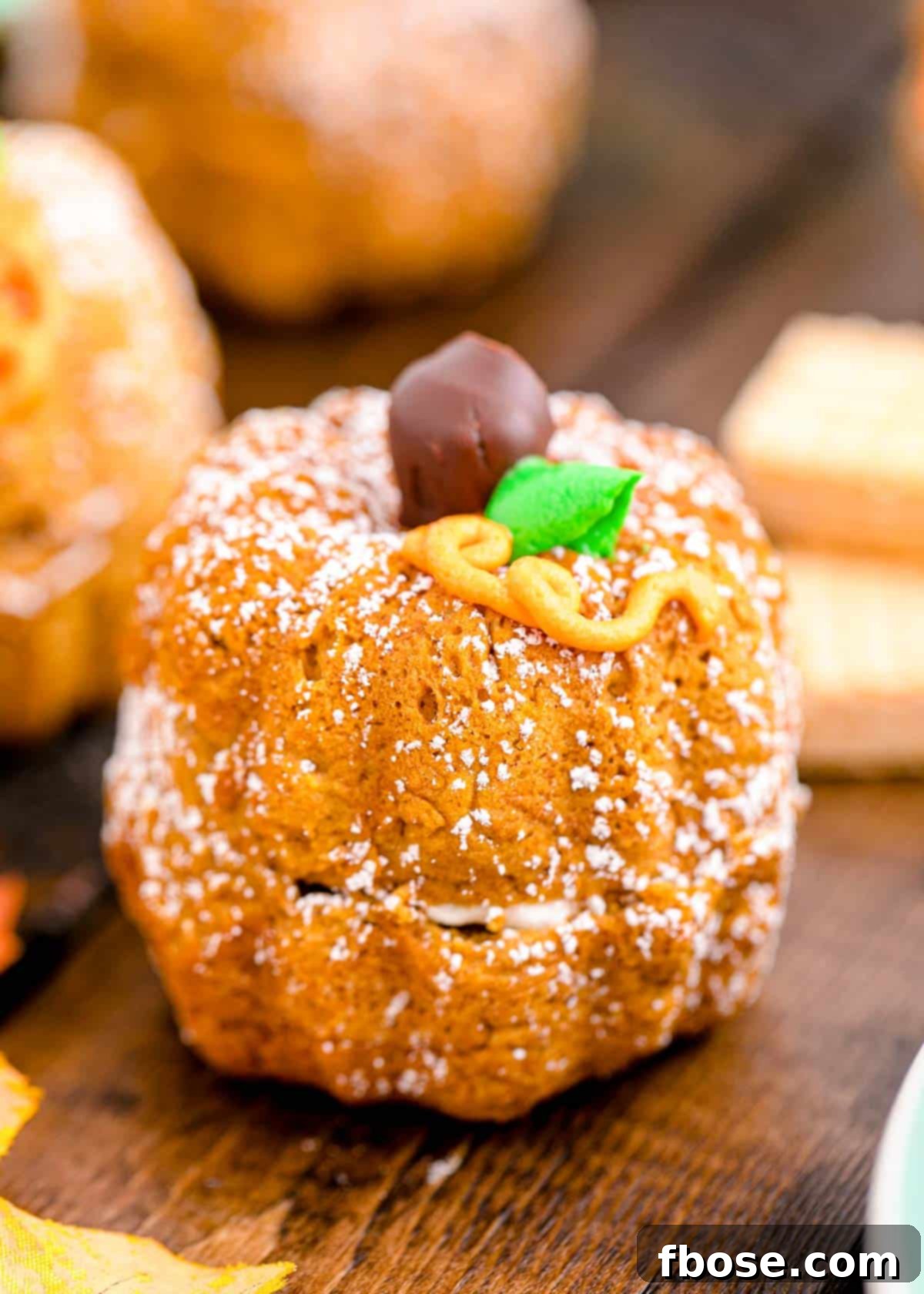 A single, beautifully decorated mini pumpkin bundt cake, shaped like a pumpkin, sits invitingly on a warm wooden table.