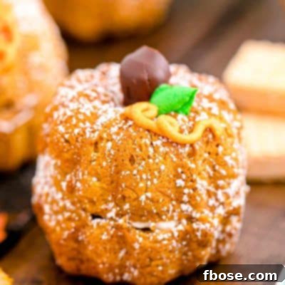 A mini pumpkin bundt cake, beautifully decorated, presented on a white and mint green plate.