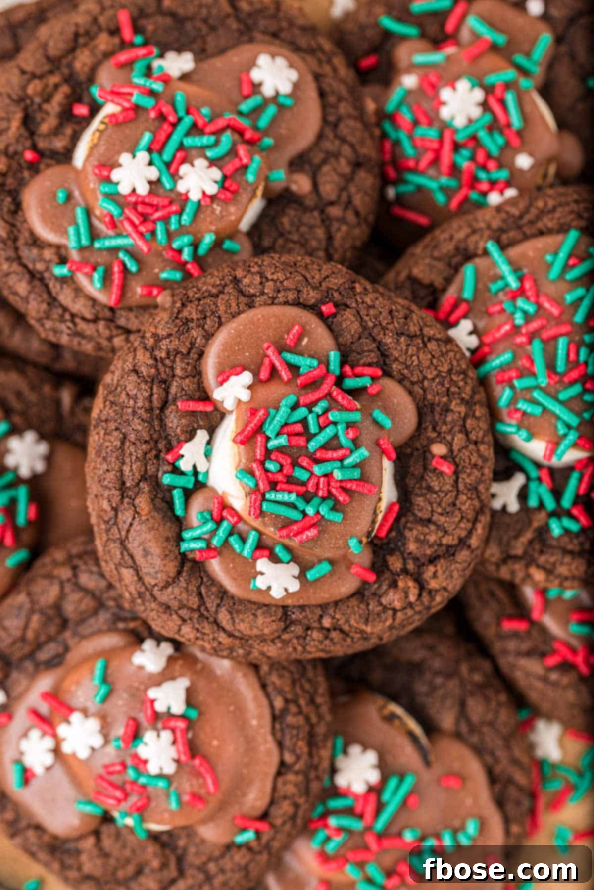 Overhead photo of hot chocolate cookies piled on top of each other, showcasing their generous marshmallow and icing.