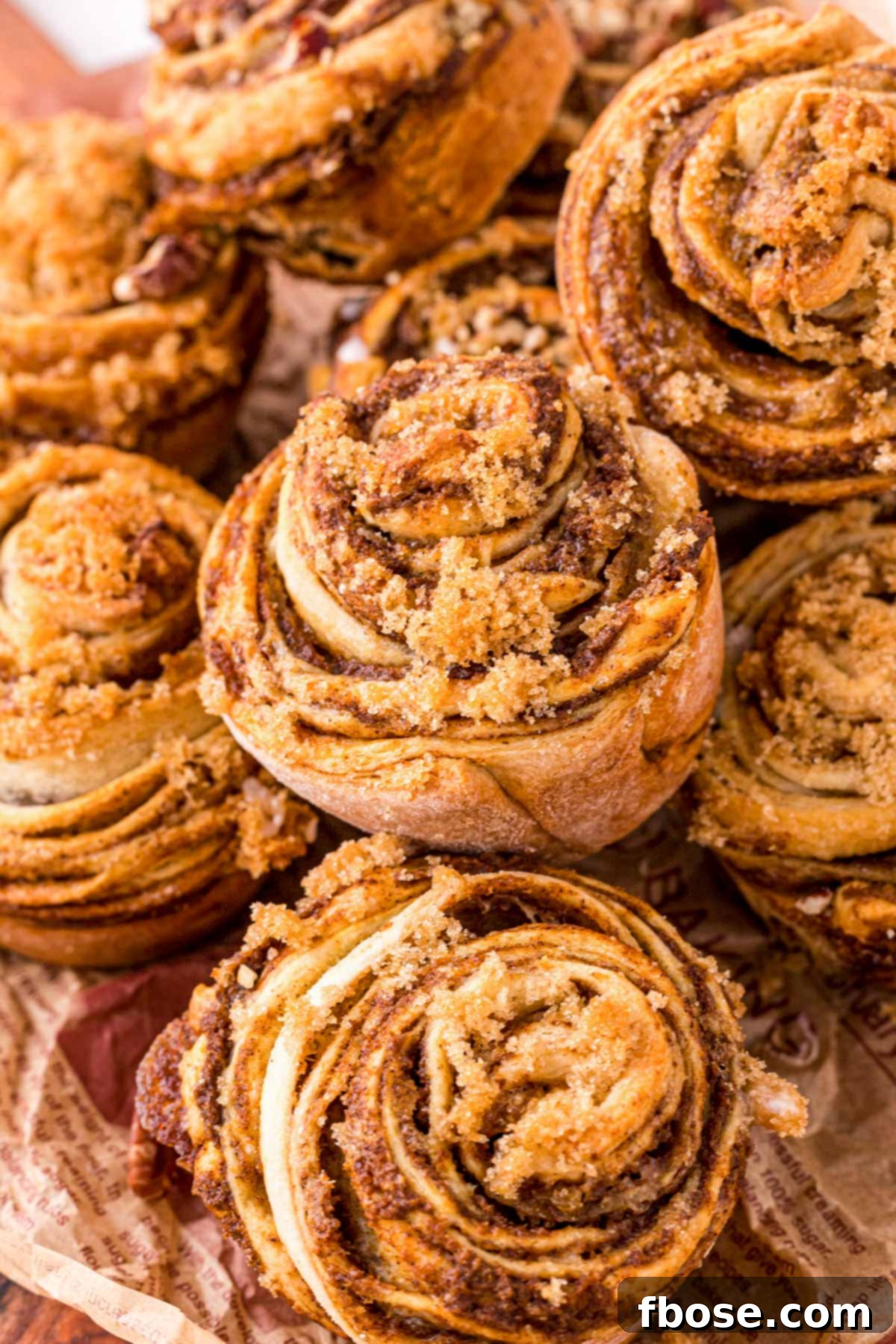 Pumpkin Cinnamon Roll Muffins piled on top of each other, showcasing their inviting golden-brown tops.