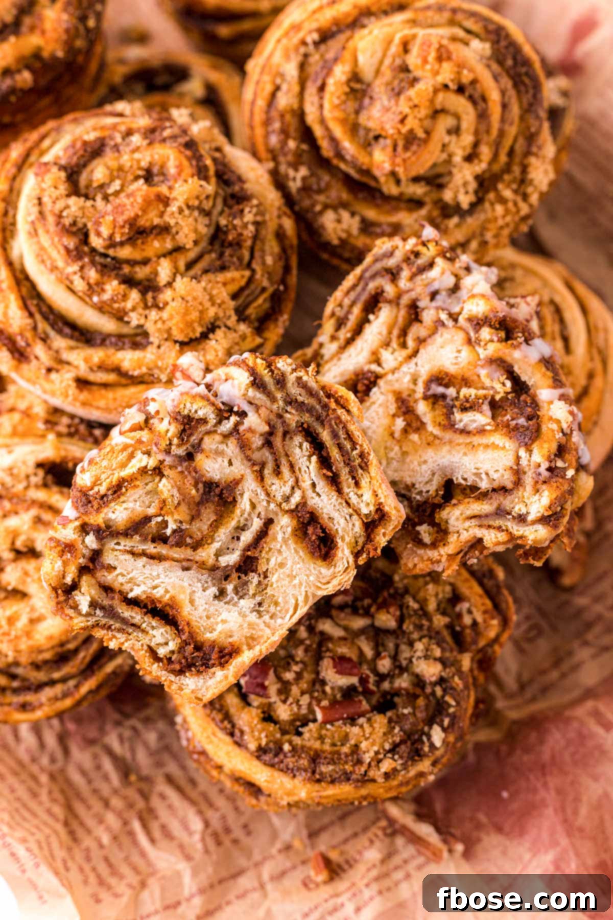 Pumpkin cinnamon rolls muffins piled, with one sliced in half to reveal the warm, spiced pumpkin filling layers.
