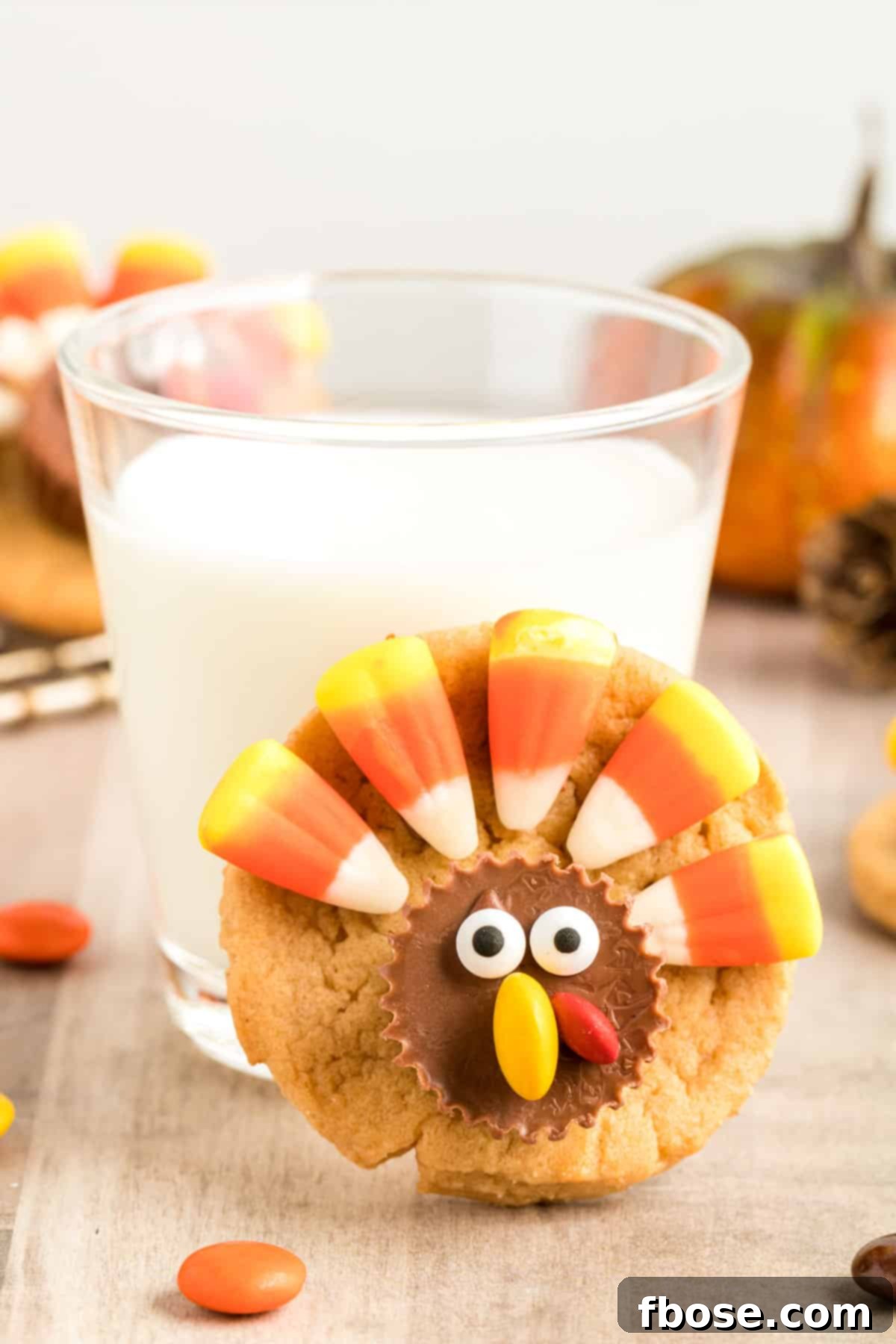 A turkey cookie leaned up against a glass of milk.