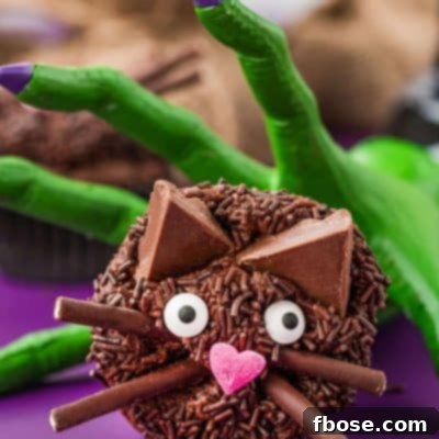 Black cat cupcakes with a green witch's hand trying to grab it.