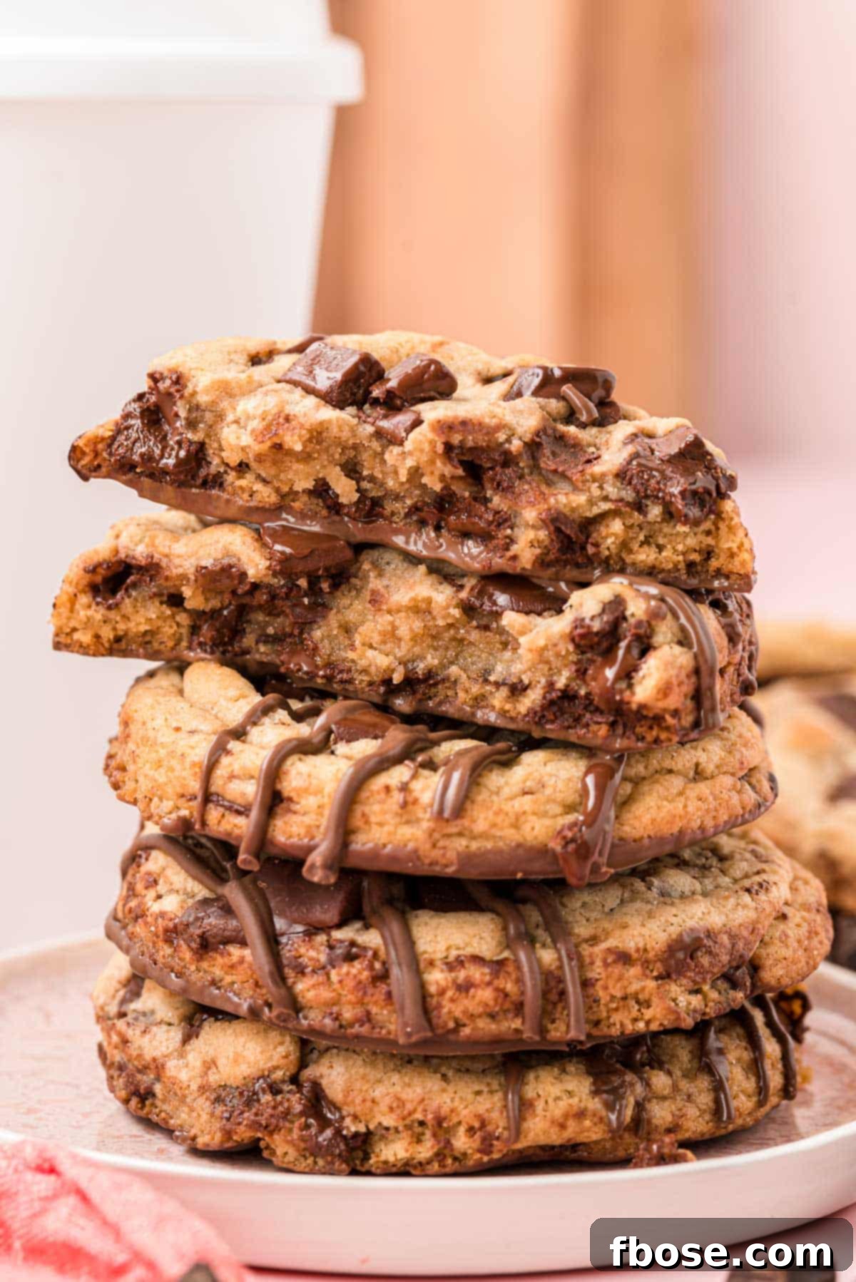The Ultimate Brown Butter Chocolate Chips 2 A stack of brown butter chocolate chip cookies on a white plate. The top cookie had been broken in half to show the inside.