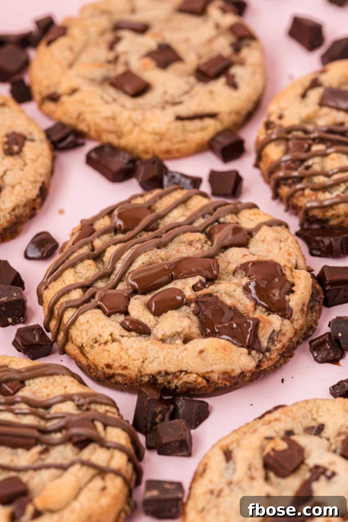 The Ultimate Brown Butter Chocolate Chips 4 Brown butter chocolate chip cookies on a pink surface.