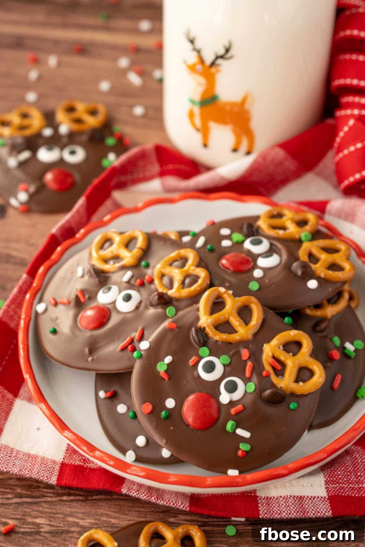 North Pole Bark 2 A small plate with festive Reindeer Christmas Bark pieces on it, with a blurred bottle of milk in the background, hinting at a cozy holiday treat.