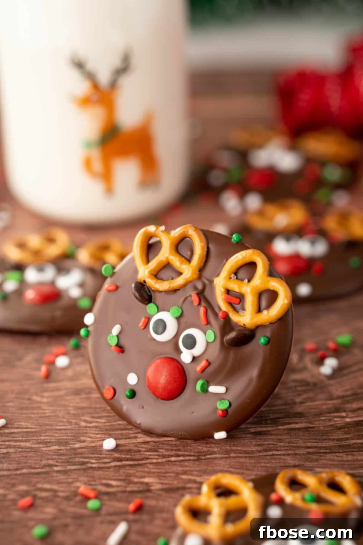 North Pole Bark 3 A charming piece of Reindeer Christmas Bark adorned with pretzels and candy eyes, resting on a rustic wooden table with more bark in the background.