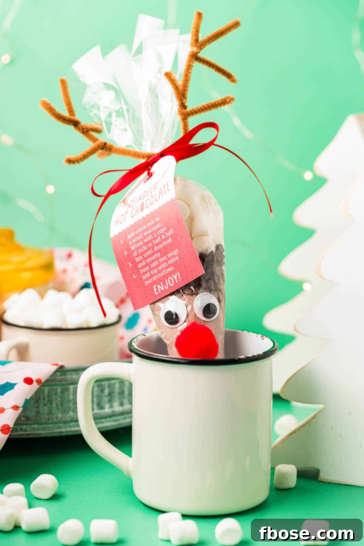 Reindeer hot chocolate cone in a white mug on a green surface.