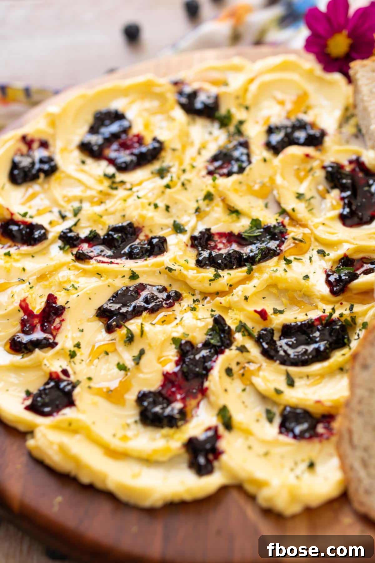 TikTok's Viral Butter Board 3 A vibrant butter board featuring swirls of Irish butter topped with blueberry jam, lemon zest, honey, and fresh basil leaves.