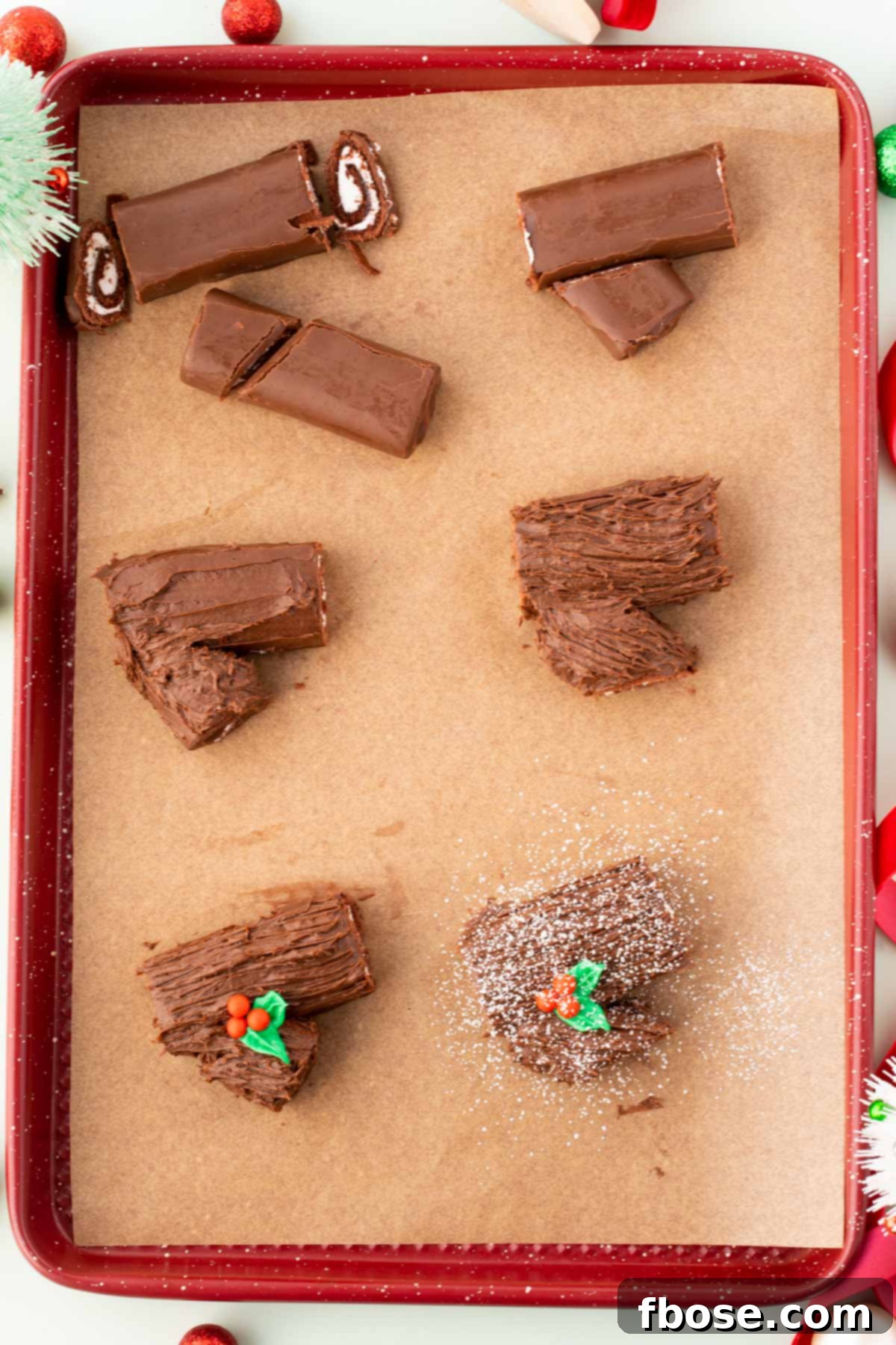 Overhead photo of a red baking sheet lined with parchment paper and swiss rolls being made into mini yule logs.