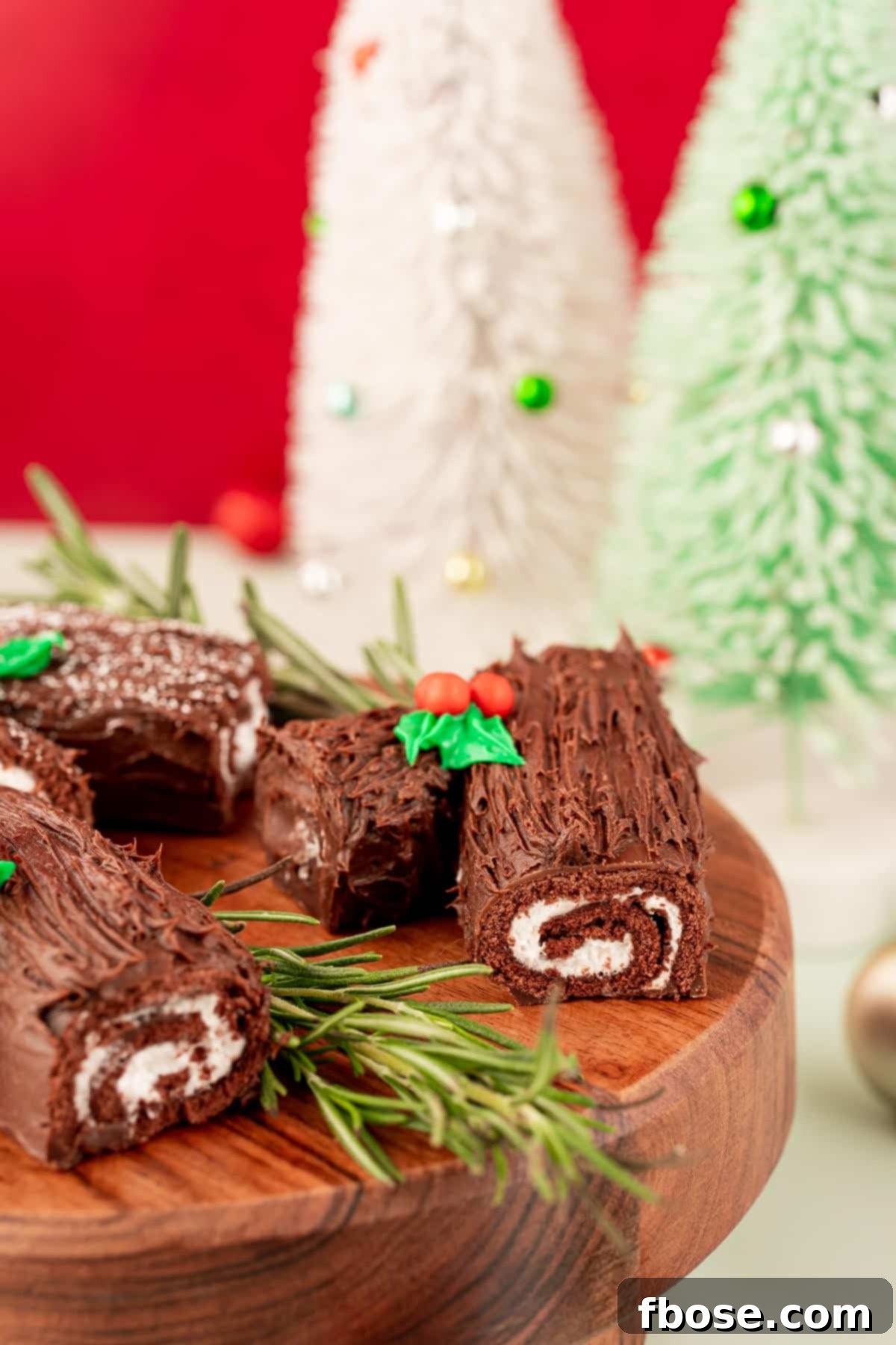 Mini yule logs made from swiss roll cakes on a wooden cake stand.