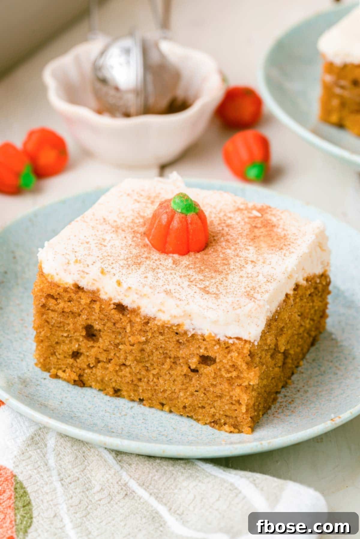 Effortless Autumn Pumpkin Bake 2 A beautifully presented slice of pumpkin snack cake on a pale blue plate, resting on a clean white table, ready to be enjoyed.