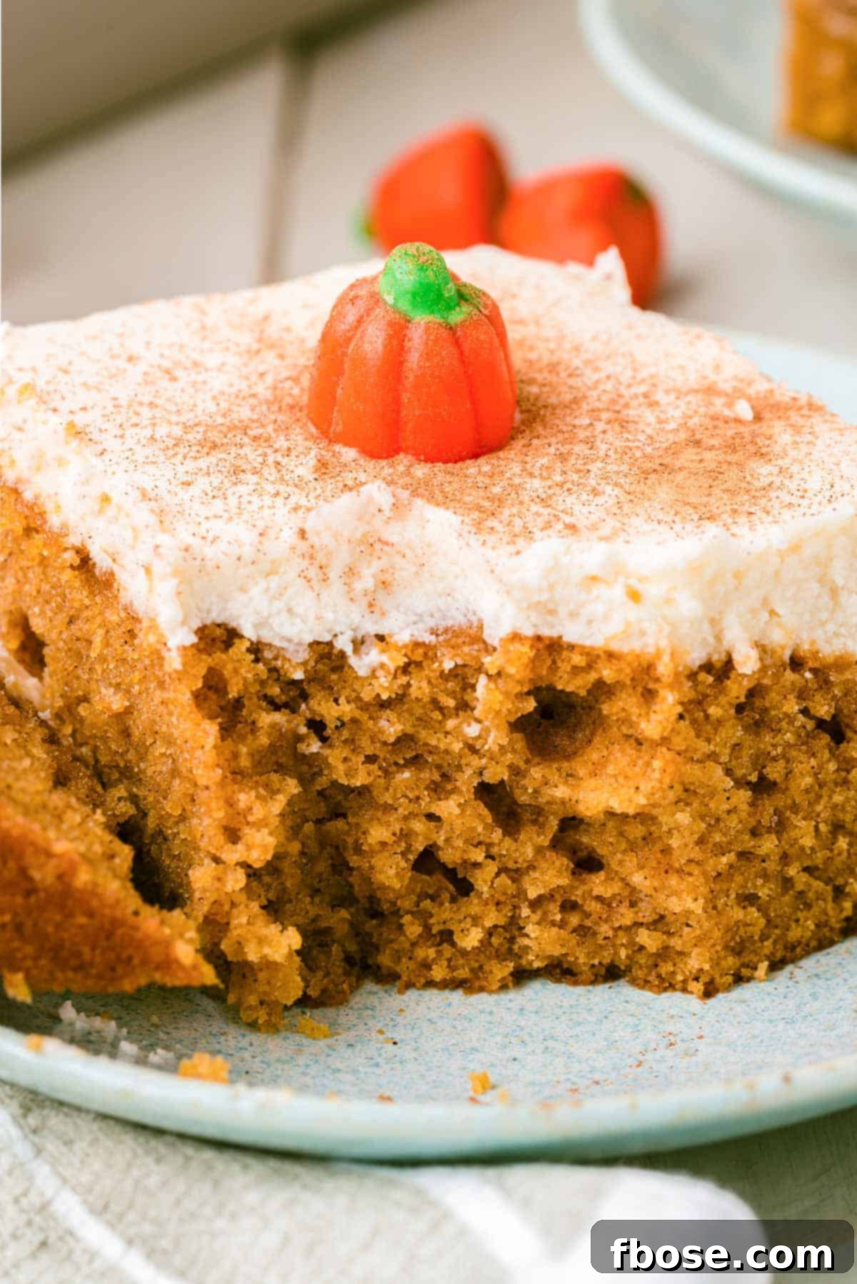Effortless Autumn Pumpkin Bake 12 A close-up shot of a slice of pumpkin cake with cream cheese frosting, showcasing a missing bite, inviting viewers to taste.