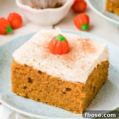 A slice of pumpkin snack cake on a pale blue plate on a white table.