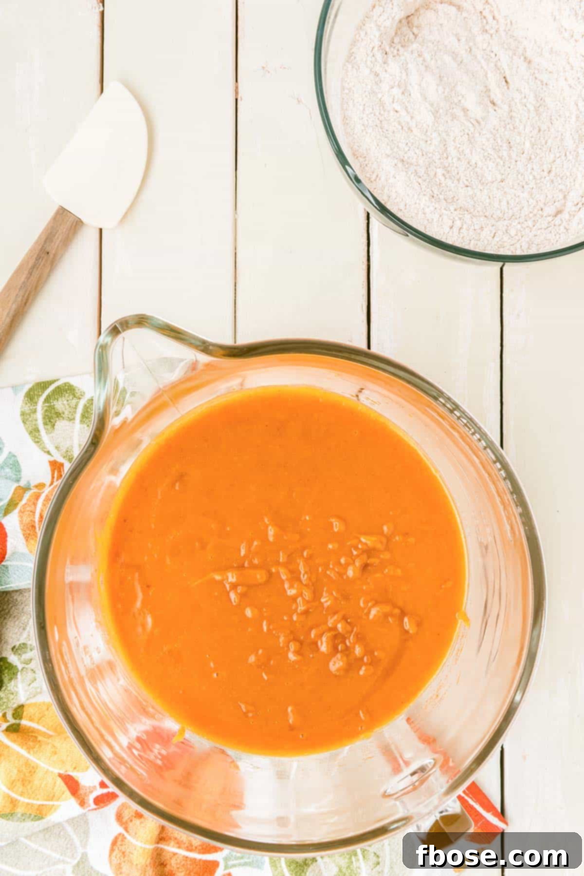 Effortless Autumn Pumpkin Bake 6 Smooth, orange-hued pumpkin cake batter swirling in a large mixing bowl, perfectly prepared for the next step.