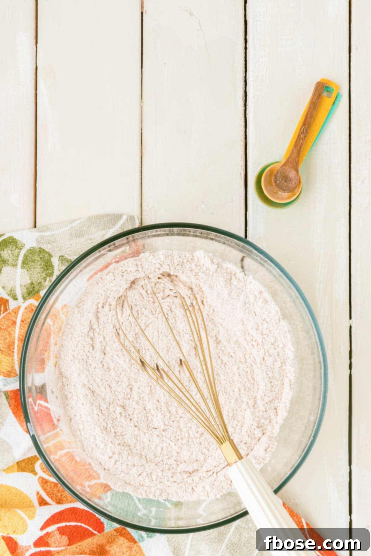 Effortless Autumn Pumpkin Bake 7 Dry ingredients for the pumpkin cake, including flour and spices, being whisked together in a bowl, creating a light, airy mixture.
