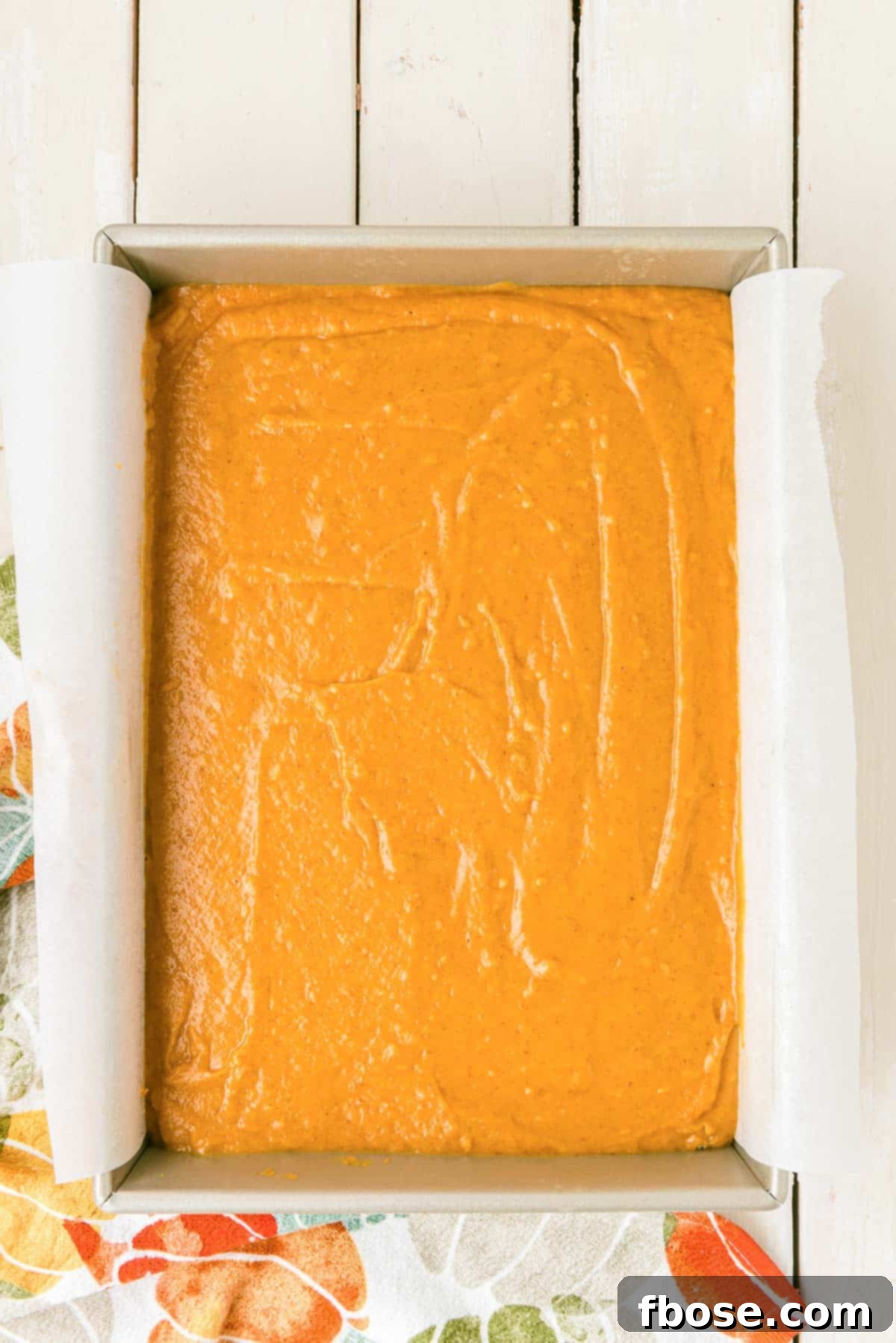 Effortless Autumn Pumpkin Bake 9 Golden-orange pumpkin cake batter smoothly poured into a parchment-lined pan, awaiting its transformation in the oven.