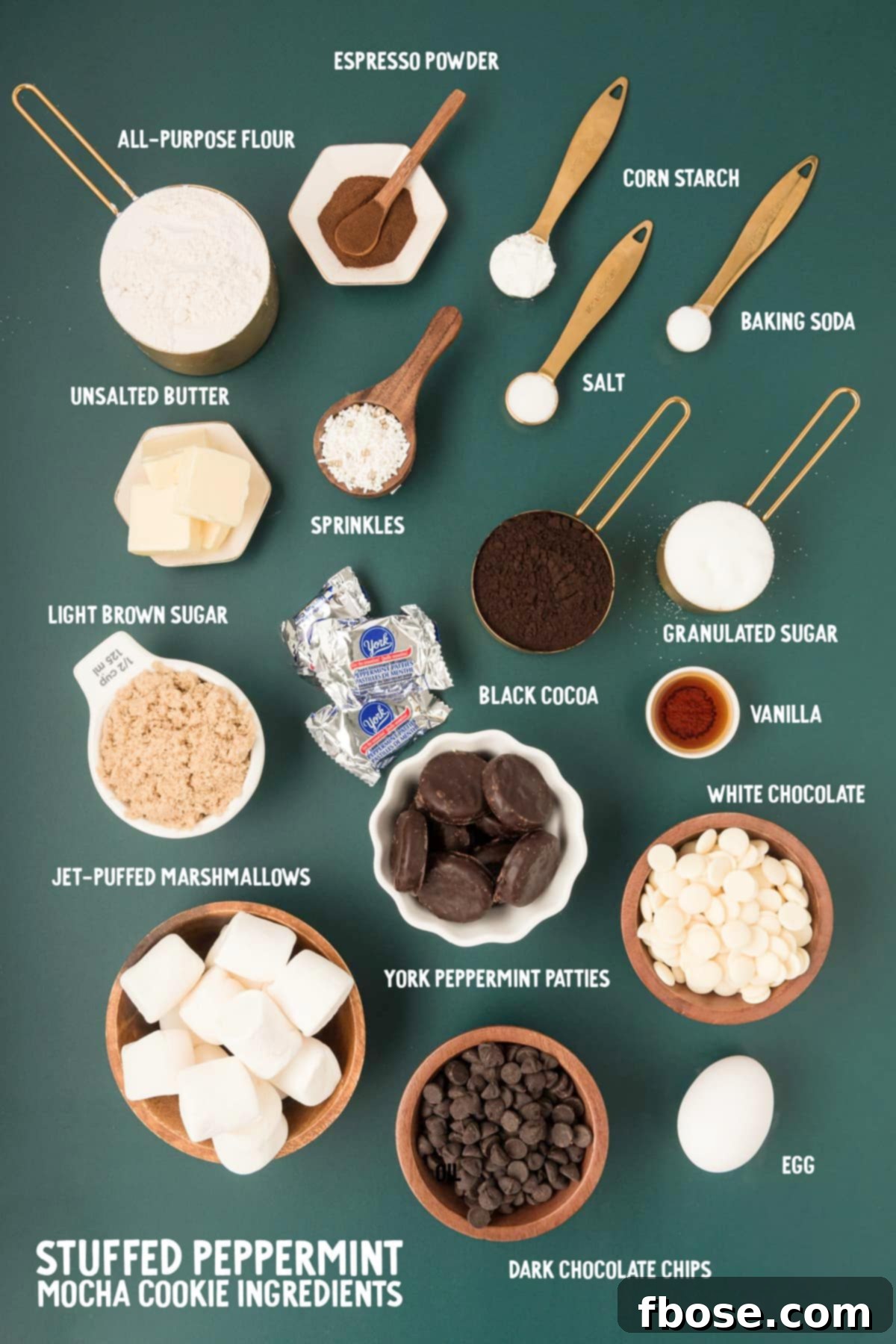 A vibrant display of fresh ingredients for Peppermint Mocha Cookies laid out on a green surface, including cocoa, flour, butter, and peppermint patties.
