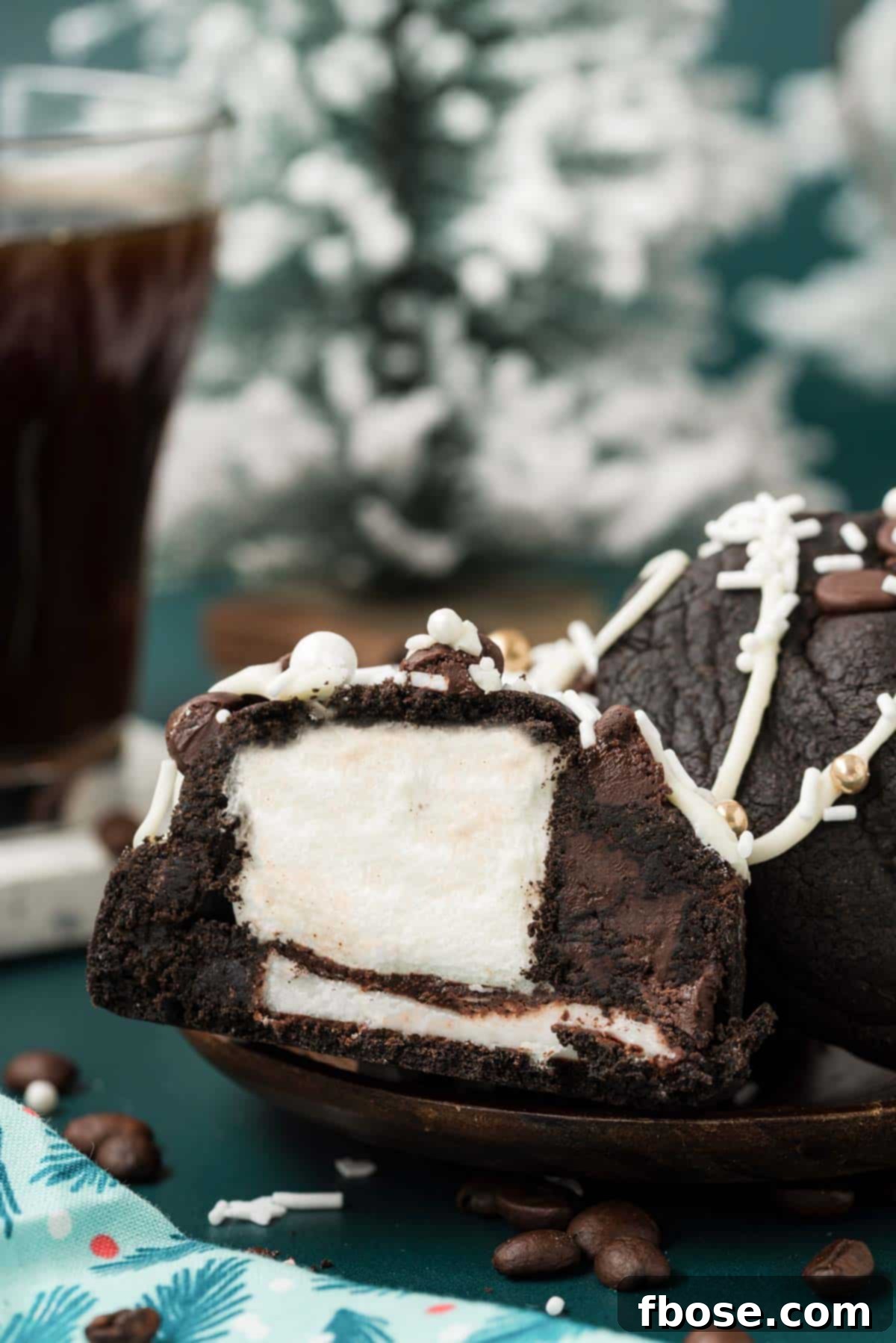 A Peppermint Mocha Cookie, beautifully sliced to reveal its luscious marshmallow and peppermint patty filling, on a wooden surface.