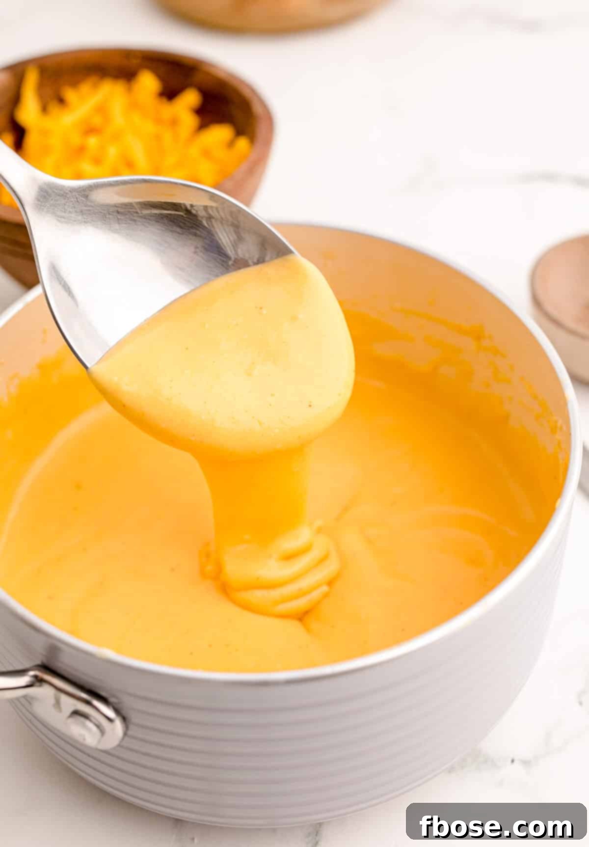 Beer cheese dip being spooned out of a saucepan, showcasing its rich, melted texture.