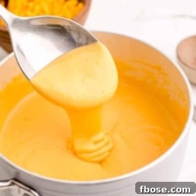 Beer cheese dip being spooned out of a saucepan.