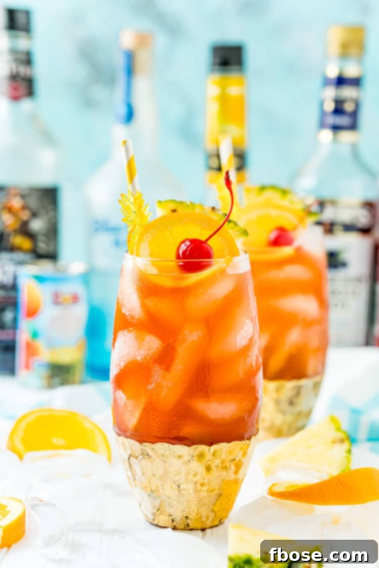 Photo of a rum runner cocktail with another drink and bottles of liqueur behind it.
