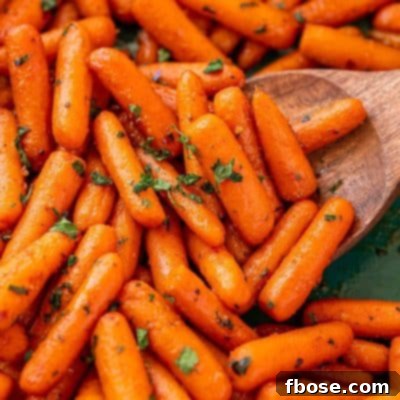 Close up of roasted glazed carrots in a teal baking dish.