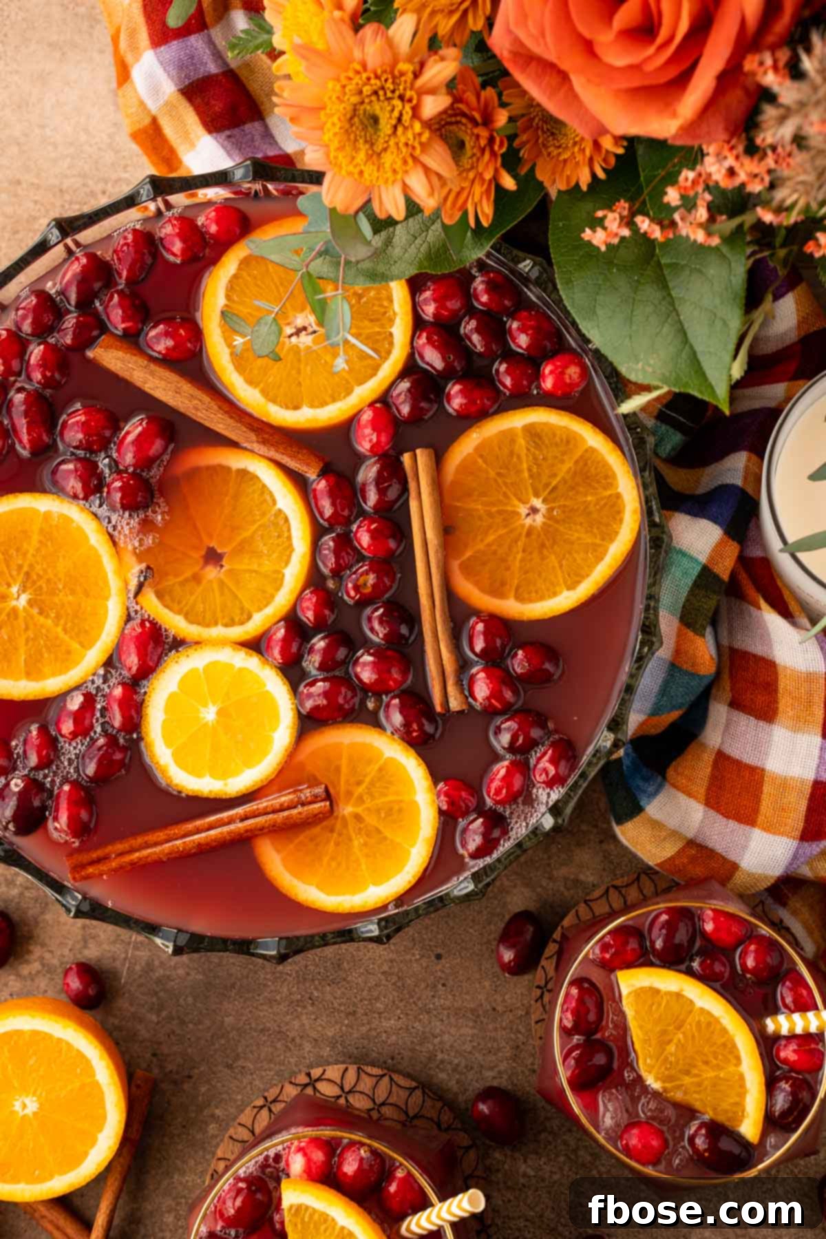 Overhead photo of a punch bowl filled with Thanksgiving punch, garnished with citrus, cinnamon, and cranberries.