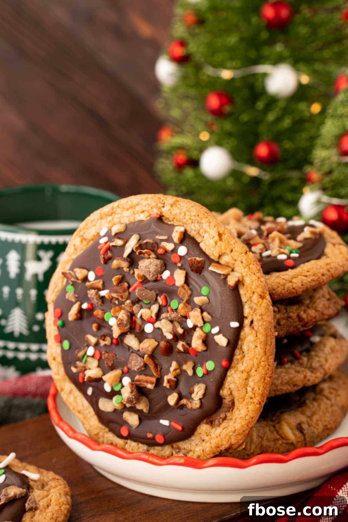 A stack of perfectly baked Christmas Crack Cookies on a festive holiday plate, with one leaning invitingly.