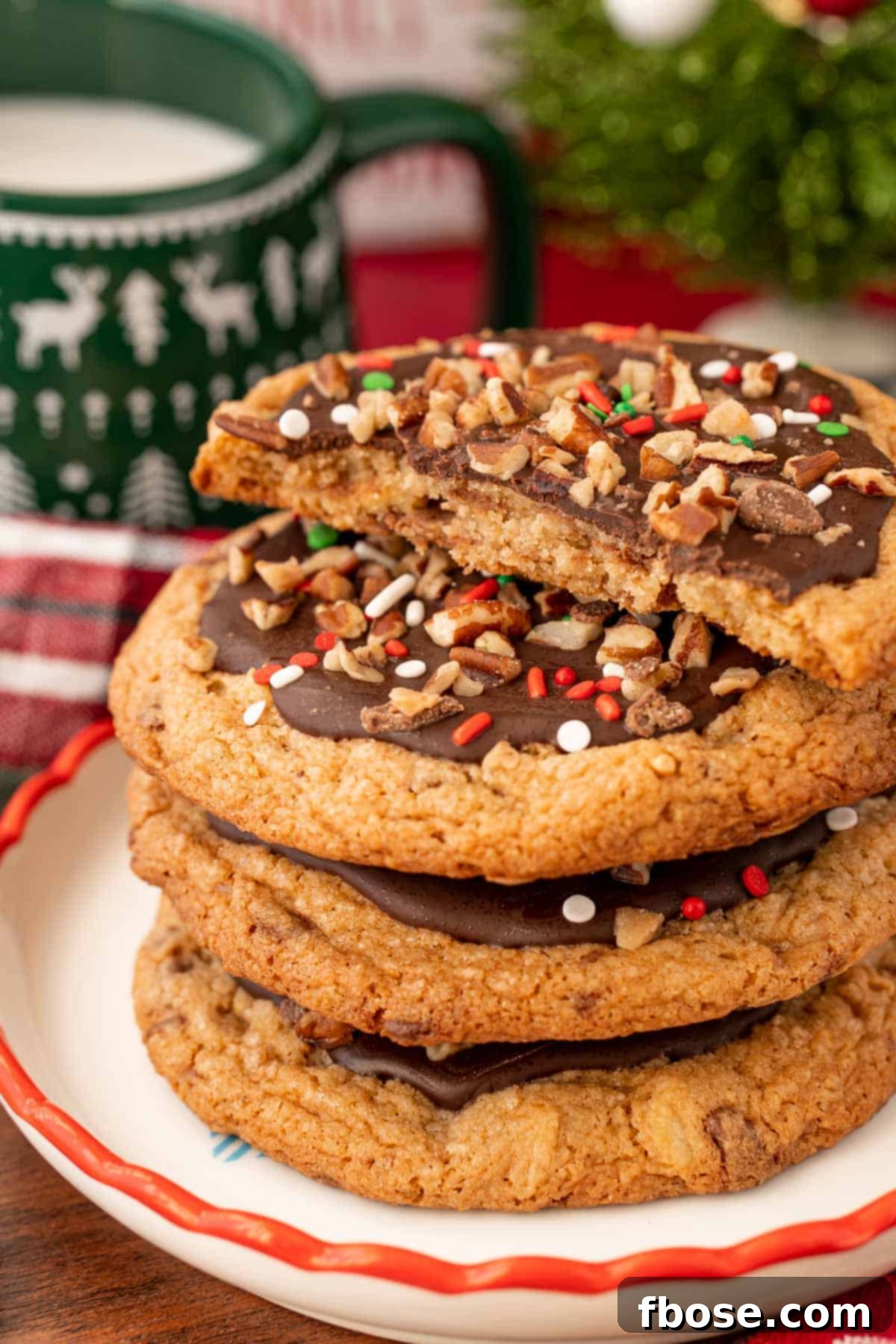 Two Christmas Crack Cookies on a holiday plate, with one broken in half to showcase its delightful texture.