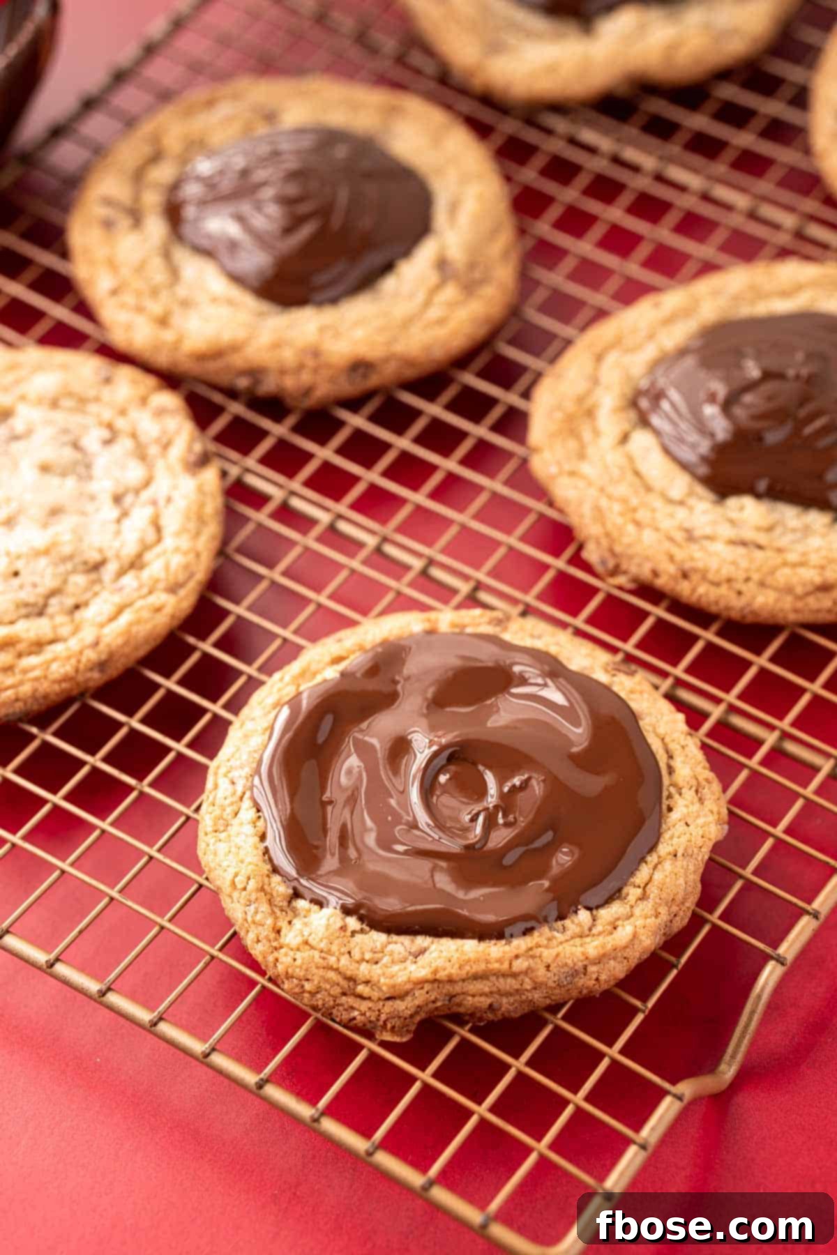 Melted chocolate generously coating the top of a freshly baked cookie, resting on a wire rack.