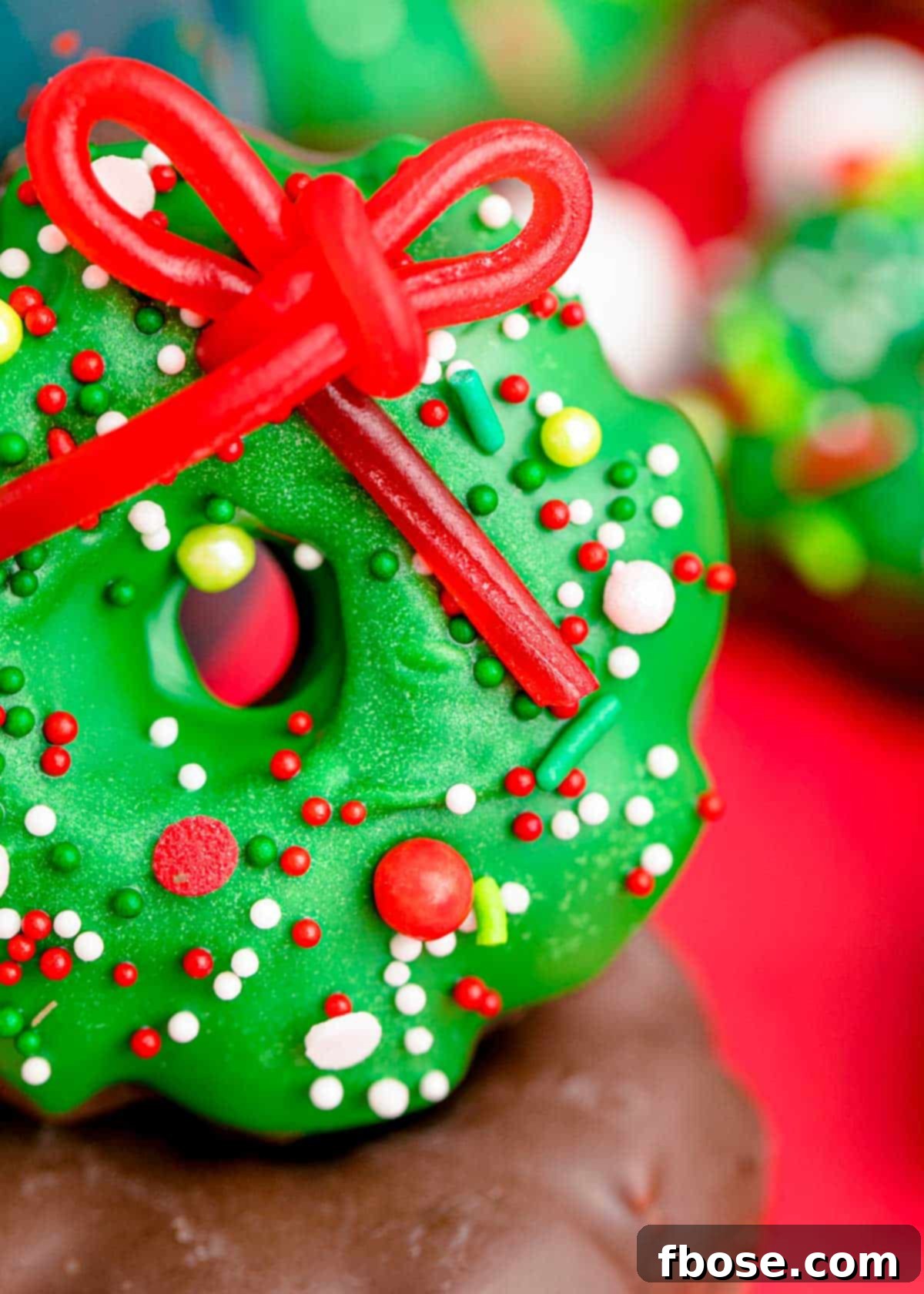 Simple Christmas Wreath Bites 6 A close-up of a single Christmas wreath cookie, highlighting the detail of the candy bow and sprinkles.