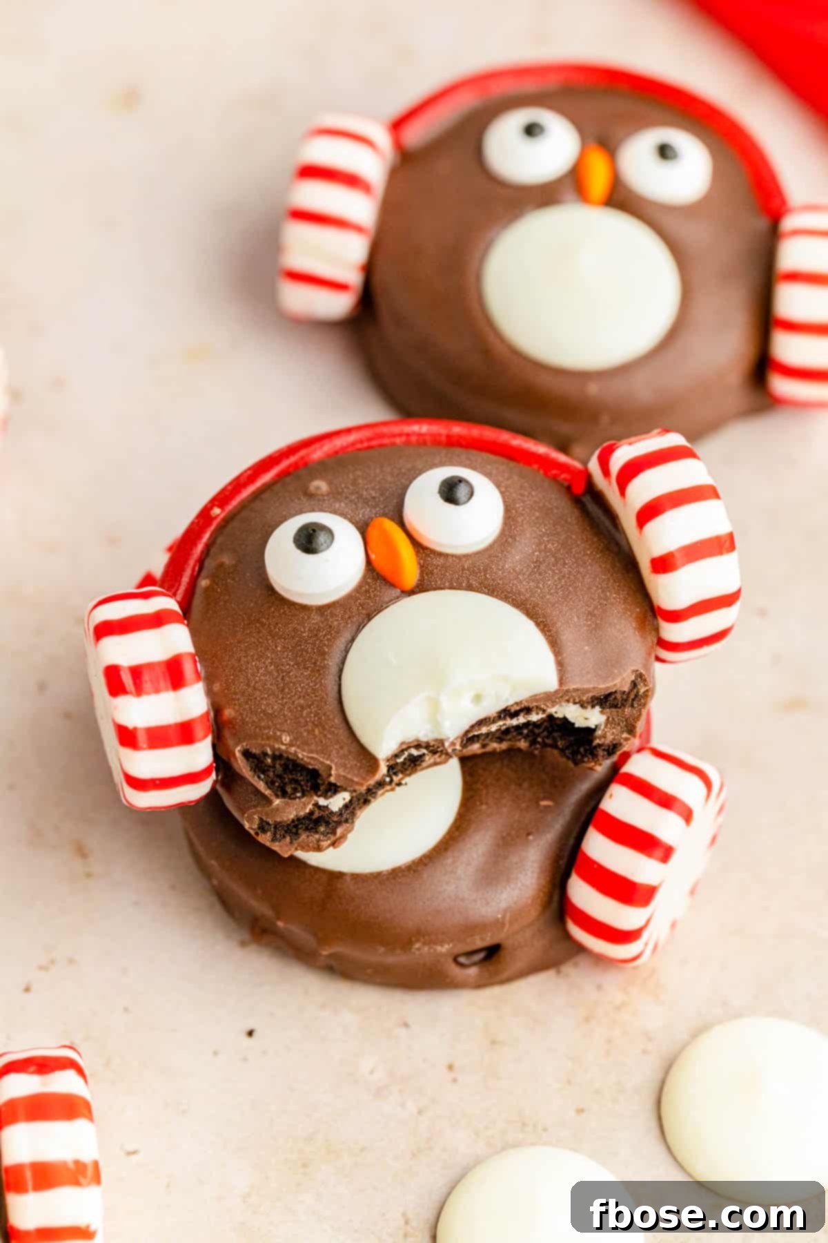 Oreo Penguin cookies on a cream colored surface.