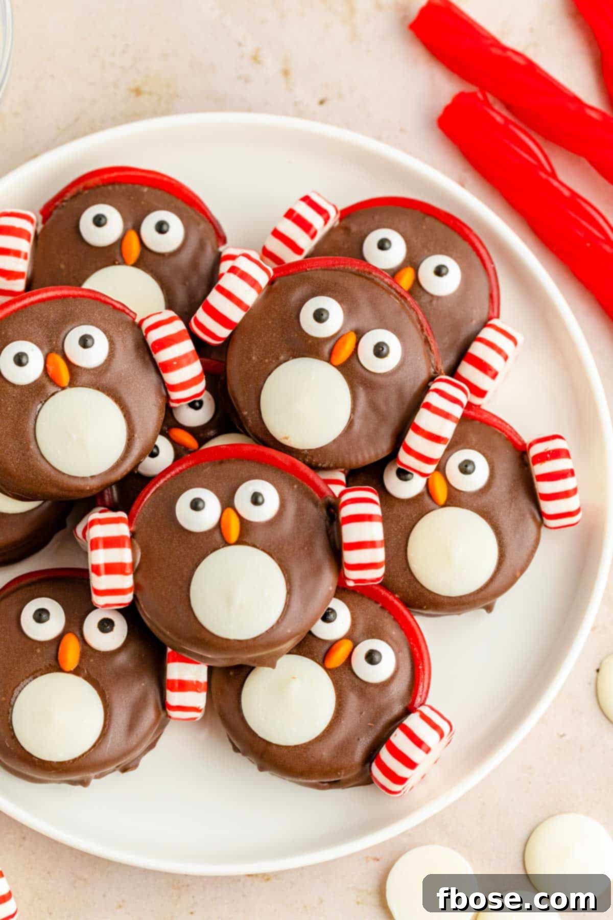 Overhead photo of chocolate covered oreos decorated like penguins on a white plate.