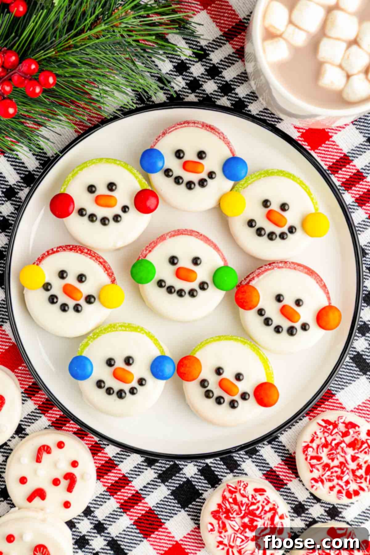 Oreo Snowman Cookies on a white plate on a plaid red and black tablecloth.