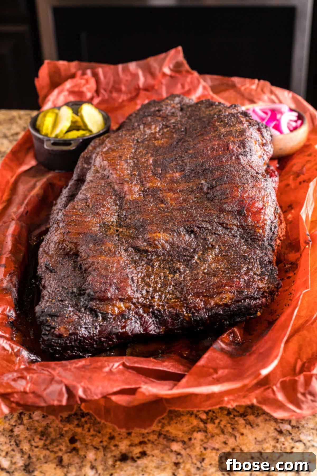 Slow-Smoked Brisket Perfection 5 A whole smoked beef brisket resting on butcher paper on a kitchen counter, ready for slicing.