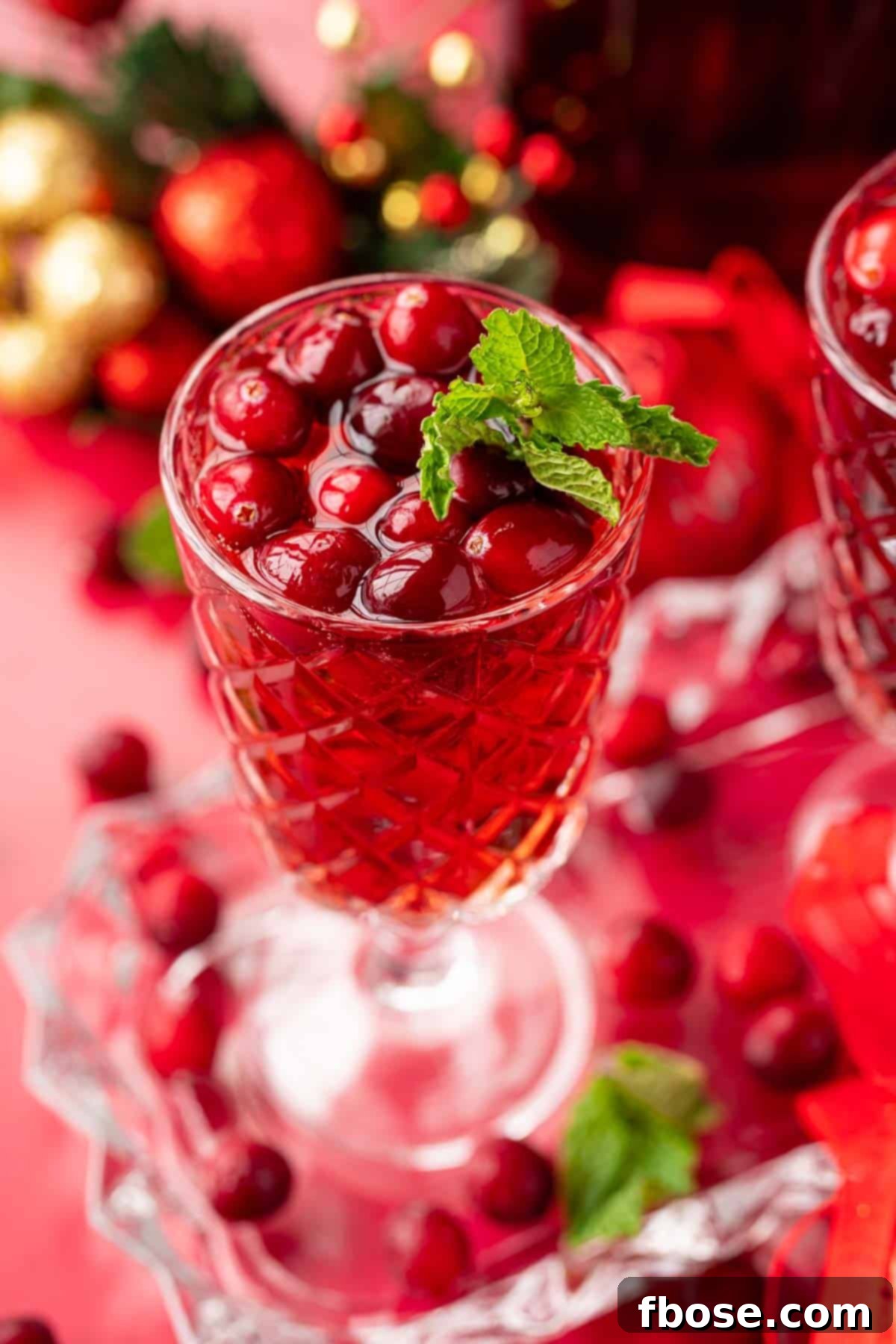 Close up of a glass of jingle juice with cranberries and mint garnish.