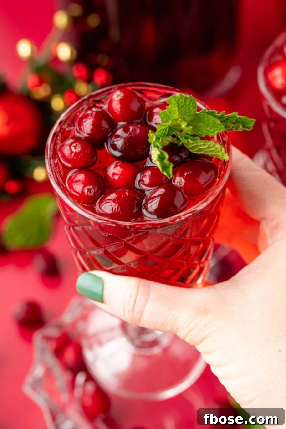 A woman's hand holding a glass of jingle juice to the camera.
