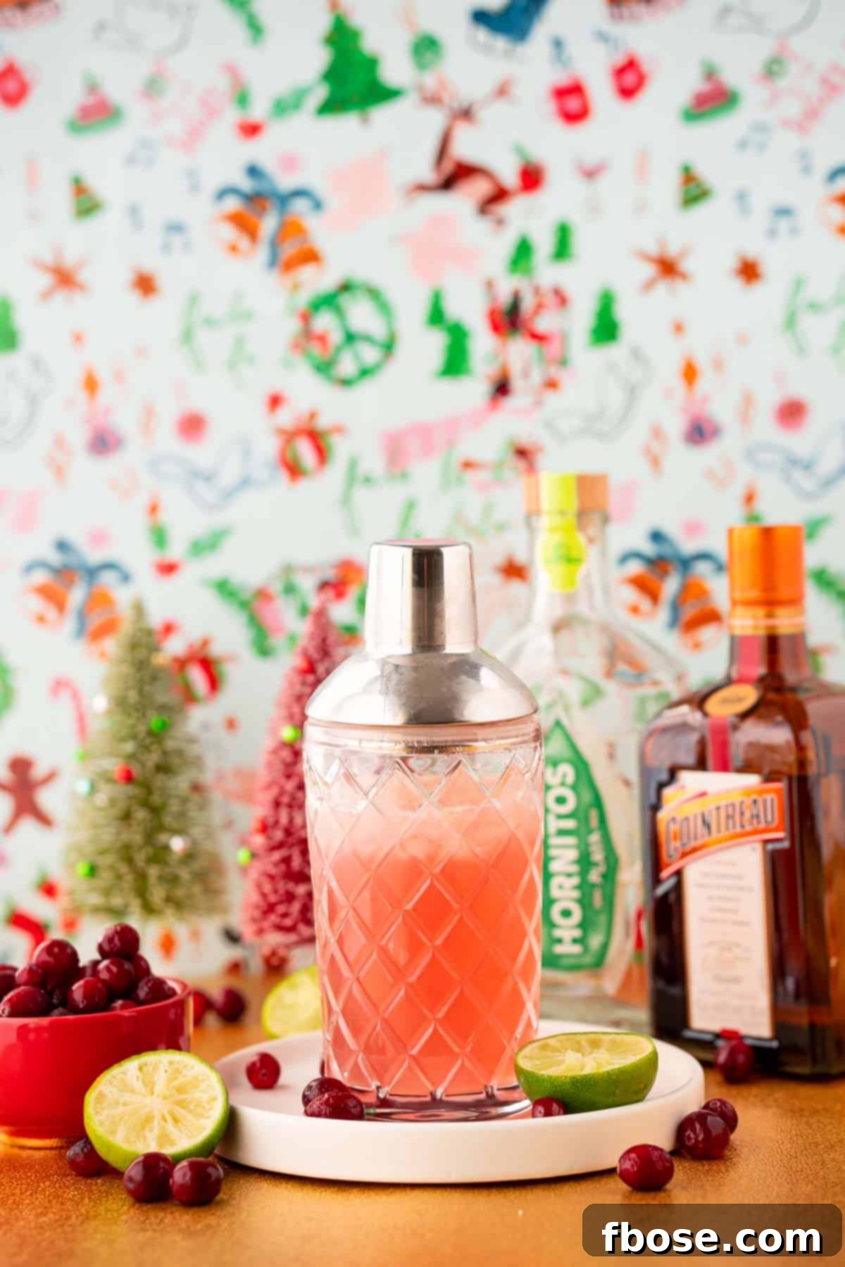 Cranberry Christmas Margarita 3 A cocktail shaker filled with cranberry margarita on a white plate.