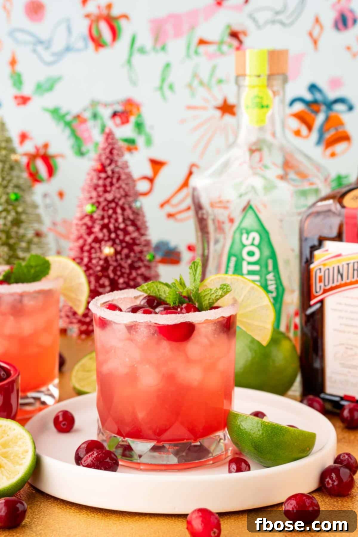 Cranberry Christmas Margarita 4 A cranberry margarita on a white tray with holiday decorations around it.