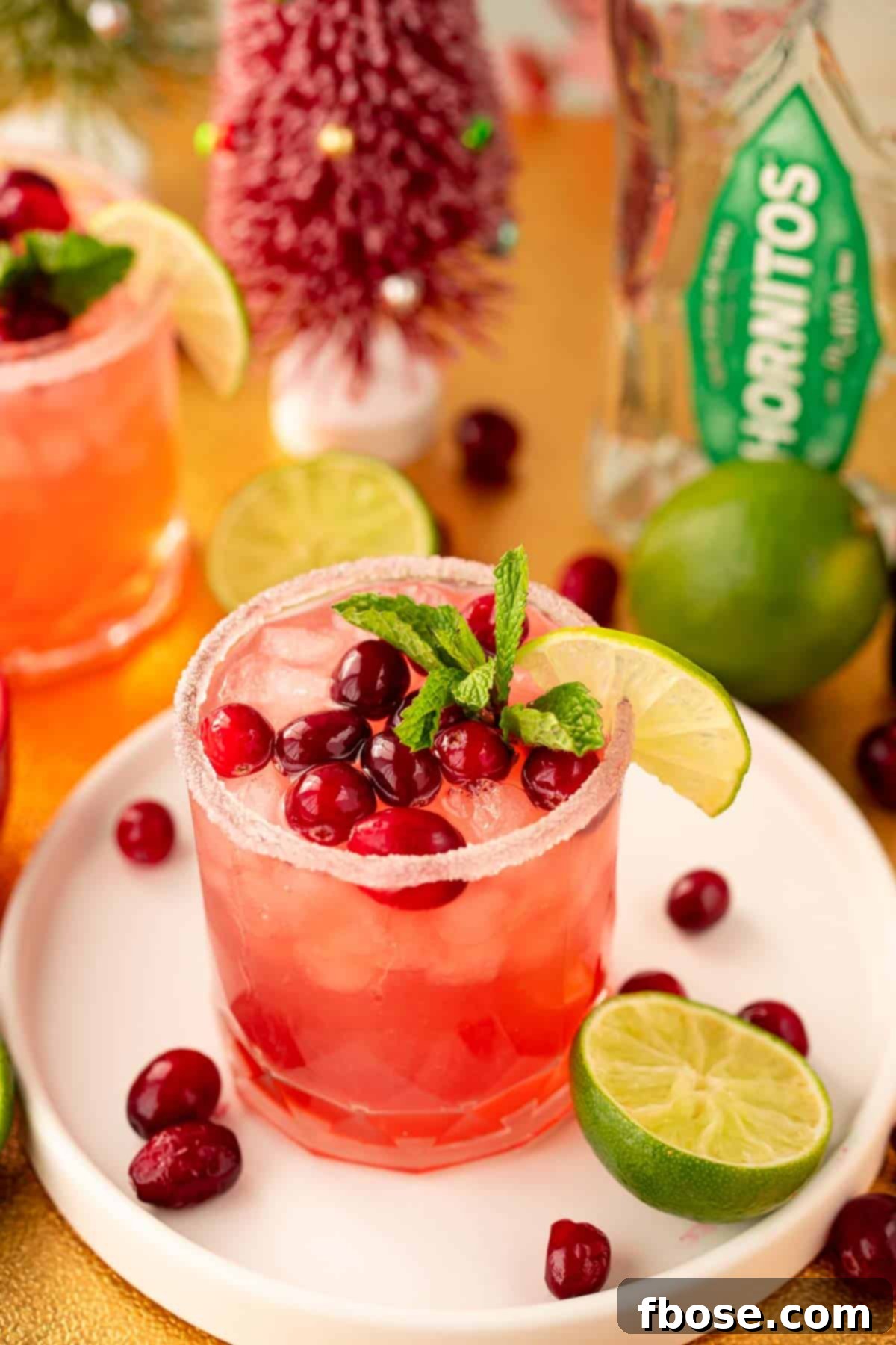 Cranberry Christmas Margarita 5 A Christmas Cranberry margarita on a white serving tray surrounded by limes and cranberries.
